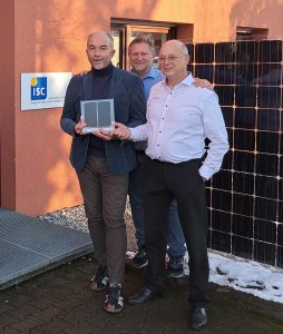 Dr. Peter Fath (RCT Holding), Dr. Radovan Kopecek and Dr. Kristian Peter (both ISC Konstanz) stand in front of the ISC Konstanz building. Dr. Kristian Peter presents Dr. Peter Fath with a mini module as a thank you for RCT's donation of 55,000 euros