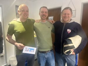 Die Kollegen im Management und Vorstand Kristian und Rado überreichen Andreas Geschenk und Karte